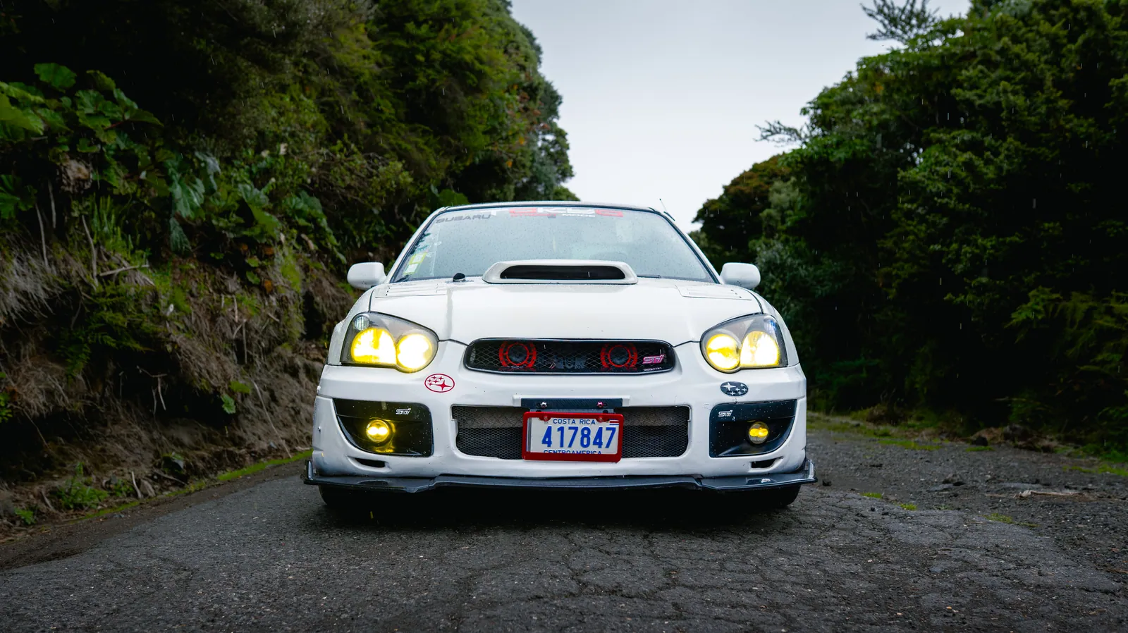 Subaru Impreza WRX/STI 2001 blanco, frontal bajo y agresivo con faros encendidos